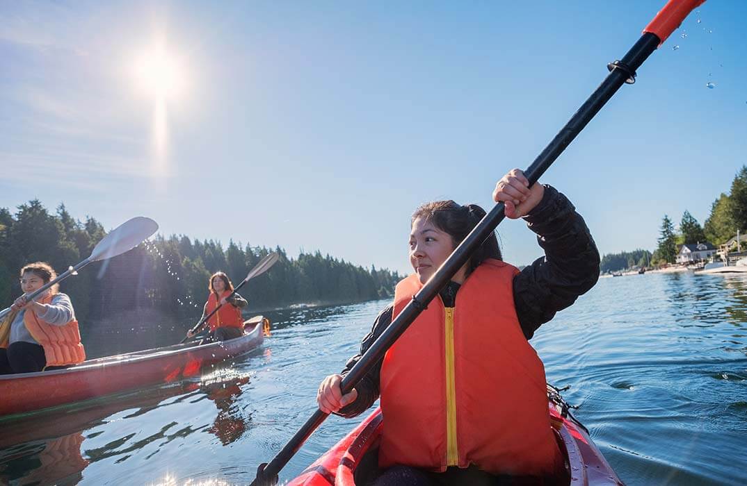 a woman in a life jacket paddling a canoe