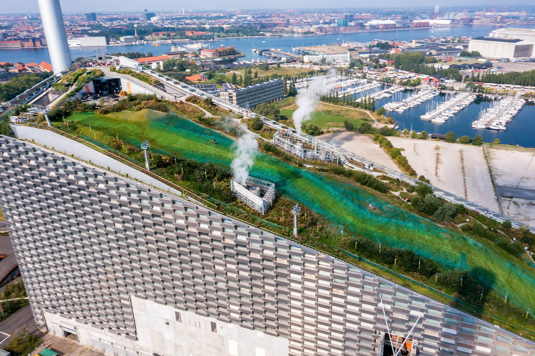 Hosts Global | Aerial view of the Amager Bakke, Copenhill Waste-to-Energy Power Plant in Copenhagen with the ski area on the roof.