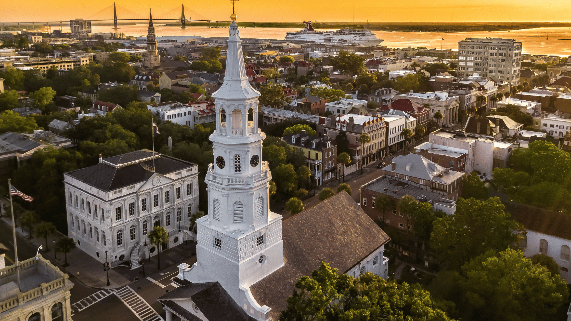 a white tower with a steeple and a city with a river and a bridge