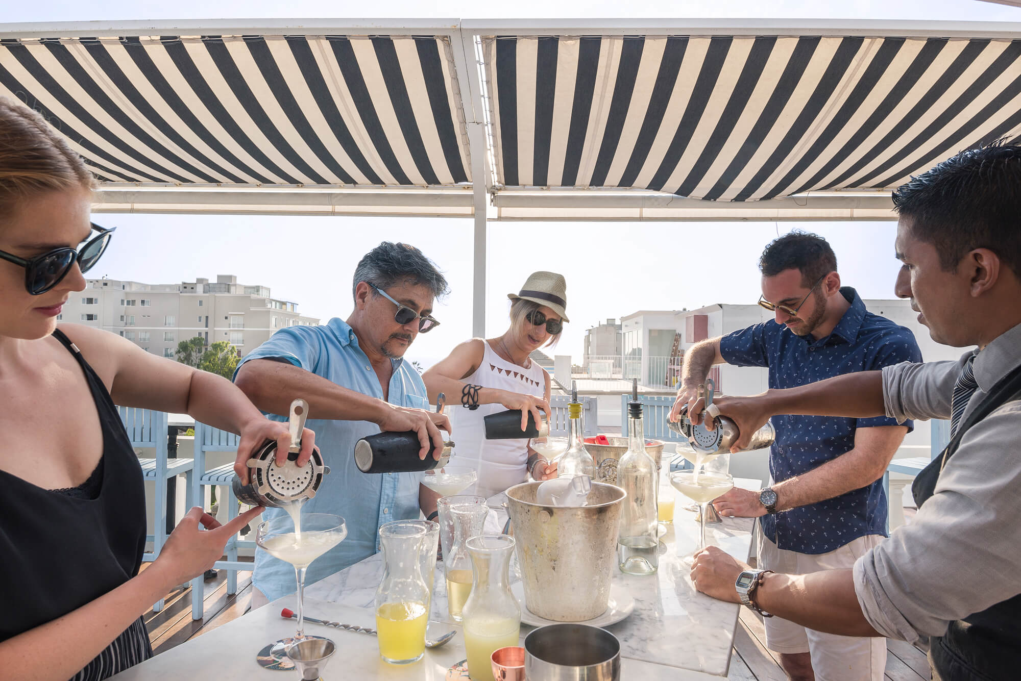 a VIP Group making cocktails taught by a mixologist on a boat outside in Brazil