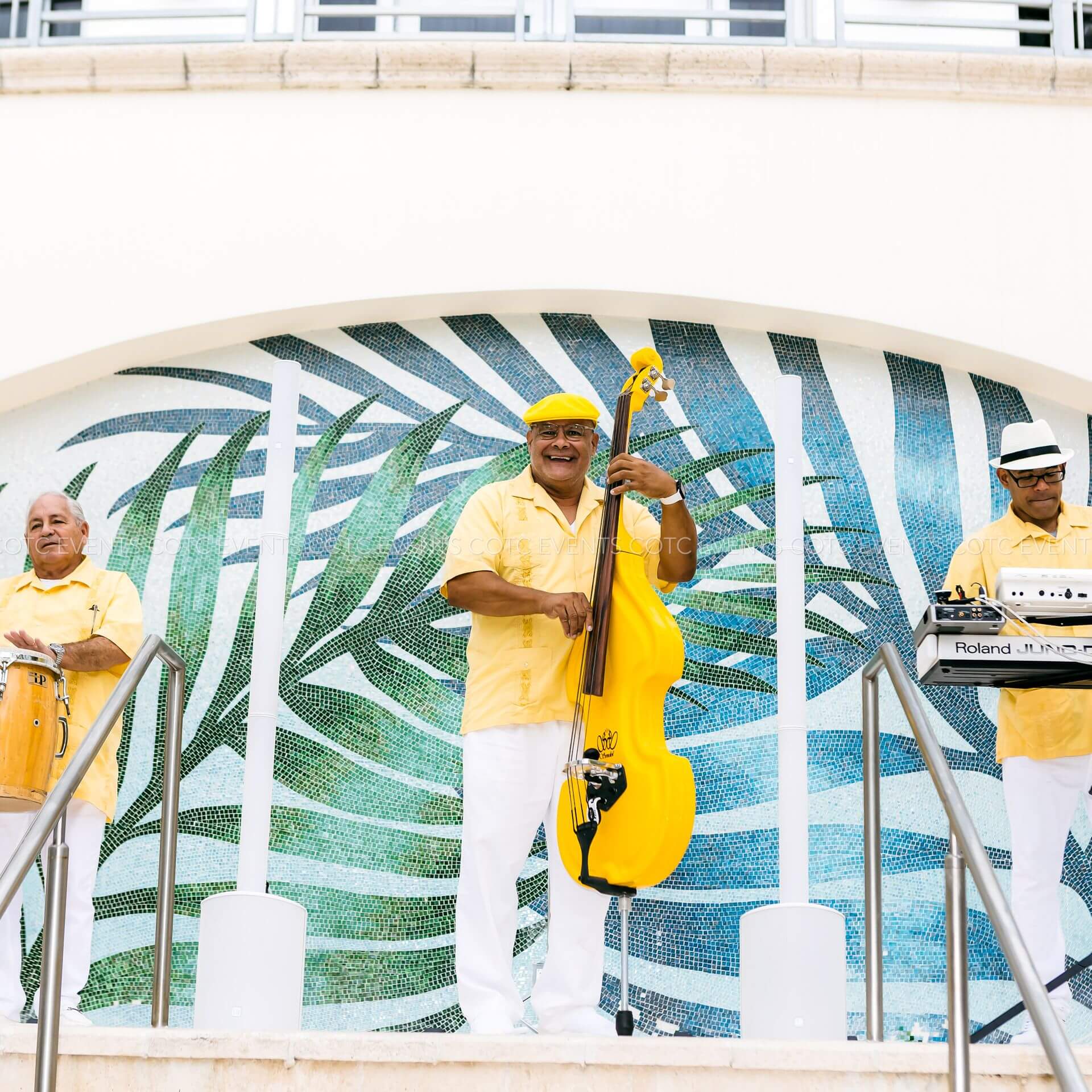 Beachy musicians playing music on a colorful wall 