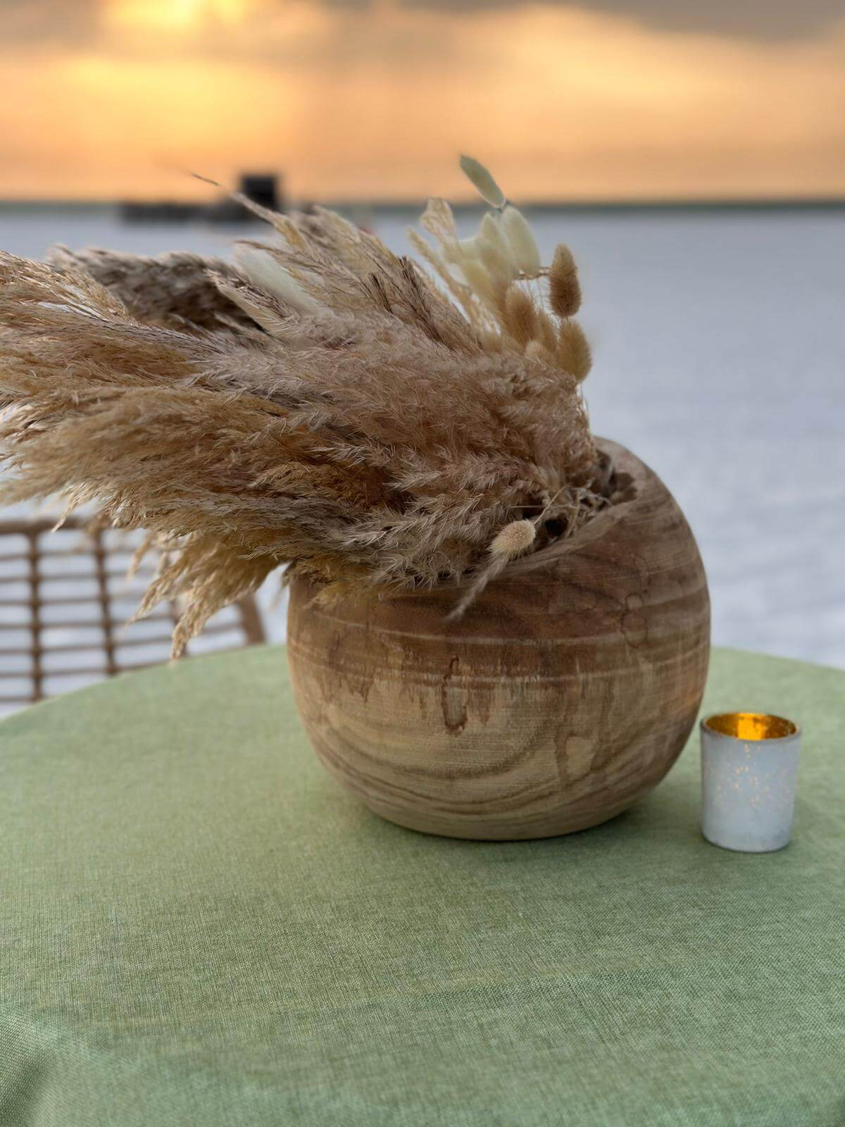 Beautiful sustainable table decor with wooden vase and pampas grass and natural materials with water backdrop