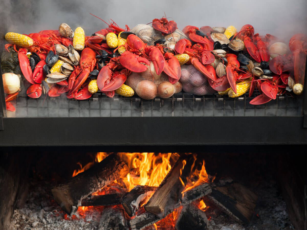 New England Clam bake with clams, oysters, lobster, potatoes, corn, onions, and garlic