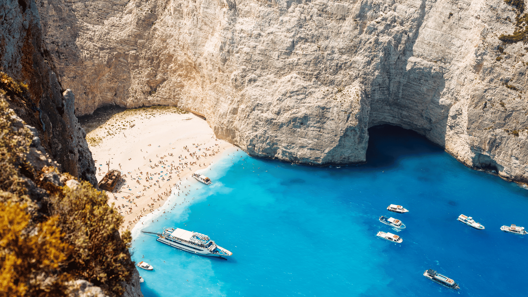 Hosts Global | Greece inlet with bright blue water and boats and rocks