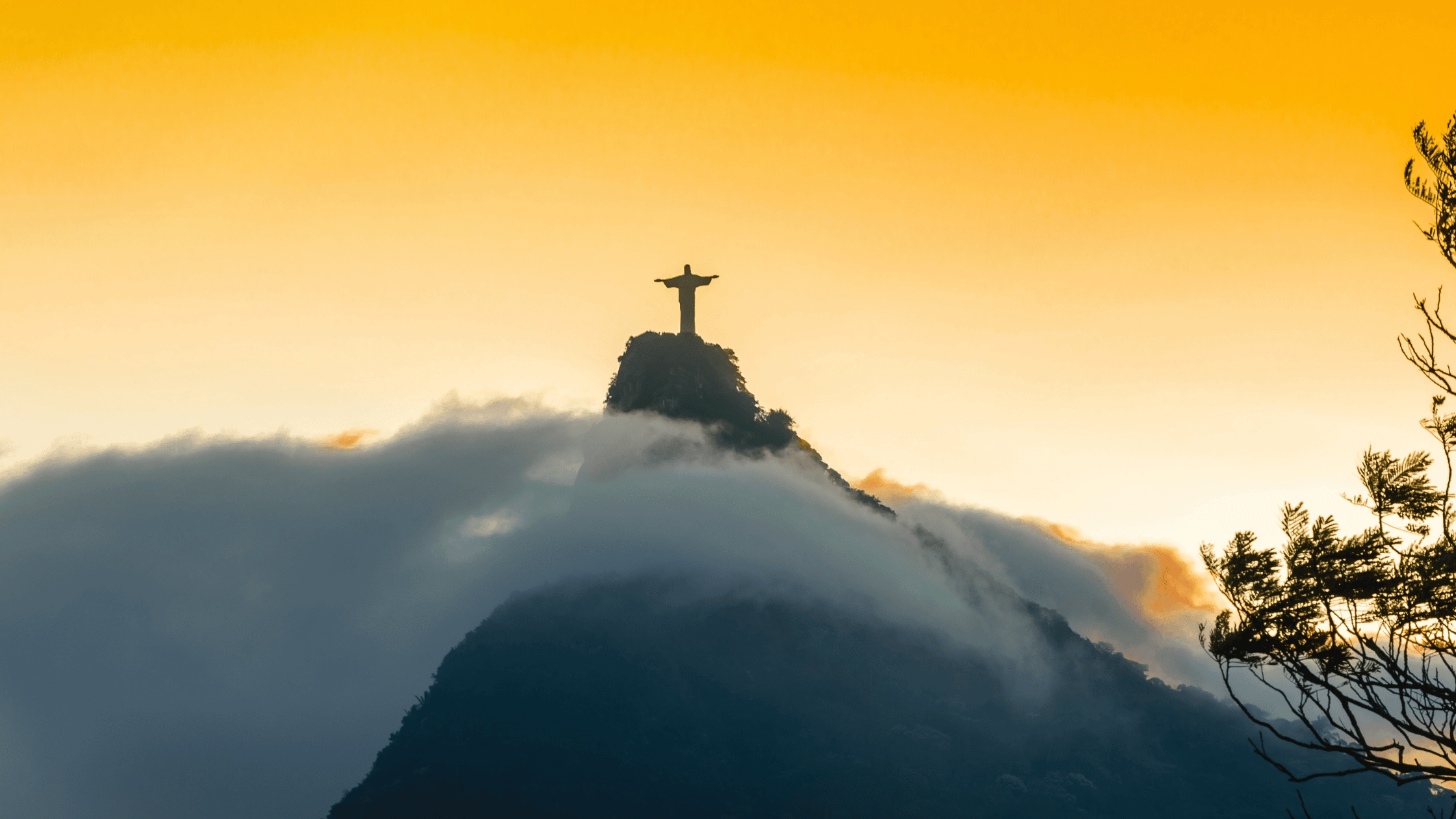 Christ the Redeemer on Corcovado Mountain, Rio de Janeiro, Brazil in sunrise with fog and clouds covering the mountain