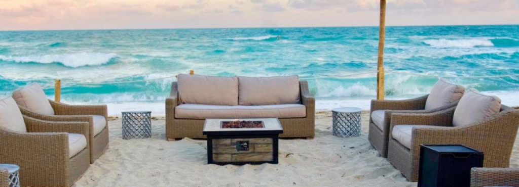 beach lounge seating on sand with turquoise blue ocean in the background