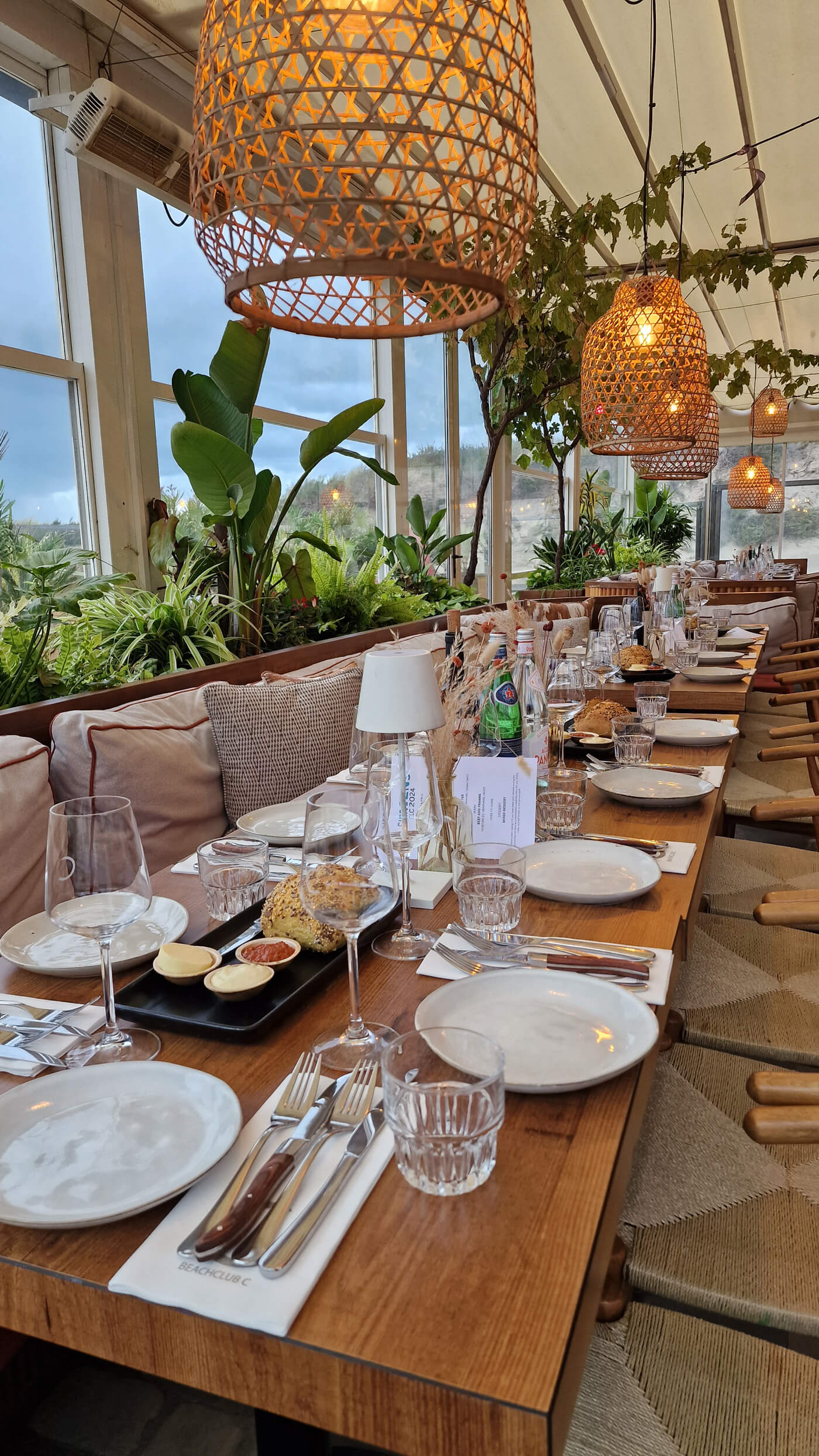 Coastal table setting with rattan lanterns and live plants and warm wood tones